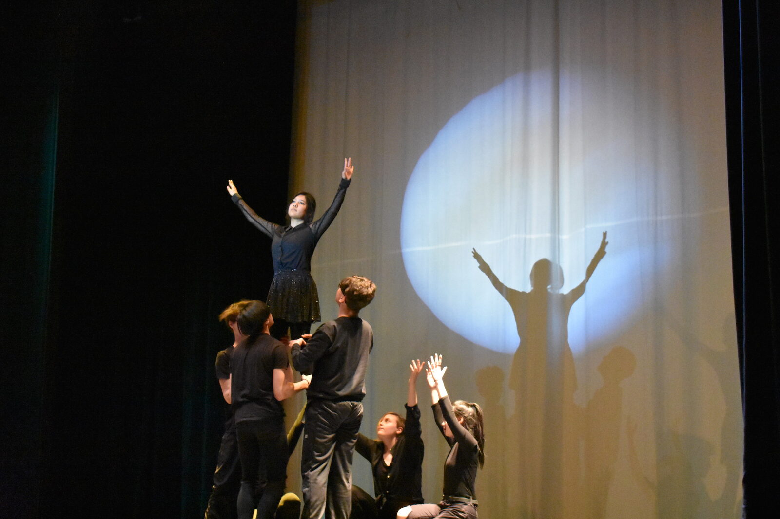 A young performer silhouetted in a spotlight on stage
